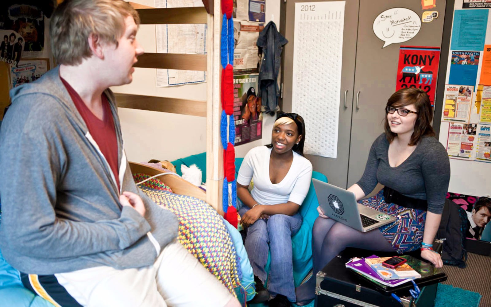 Three students laughing in a dorm room.