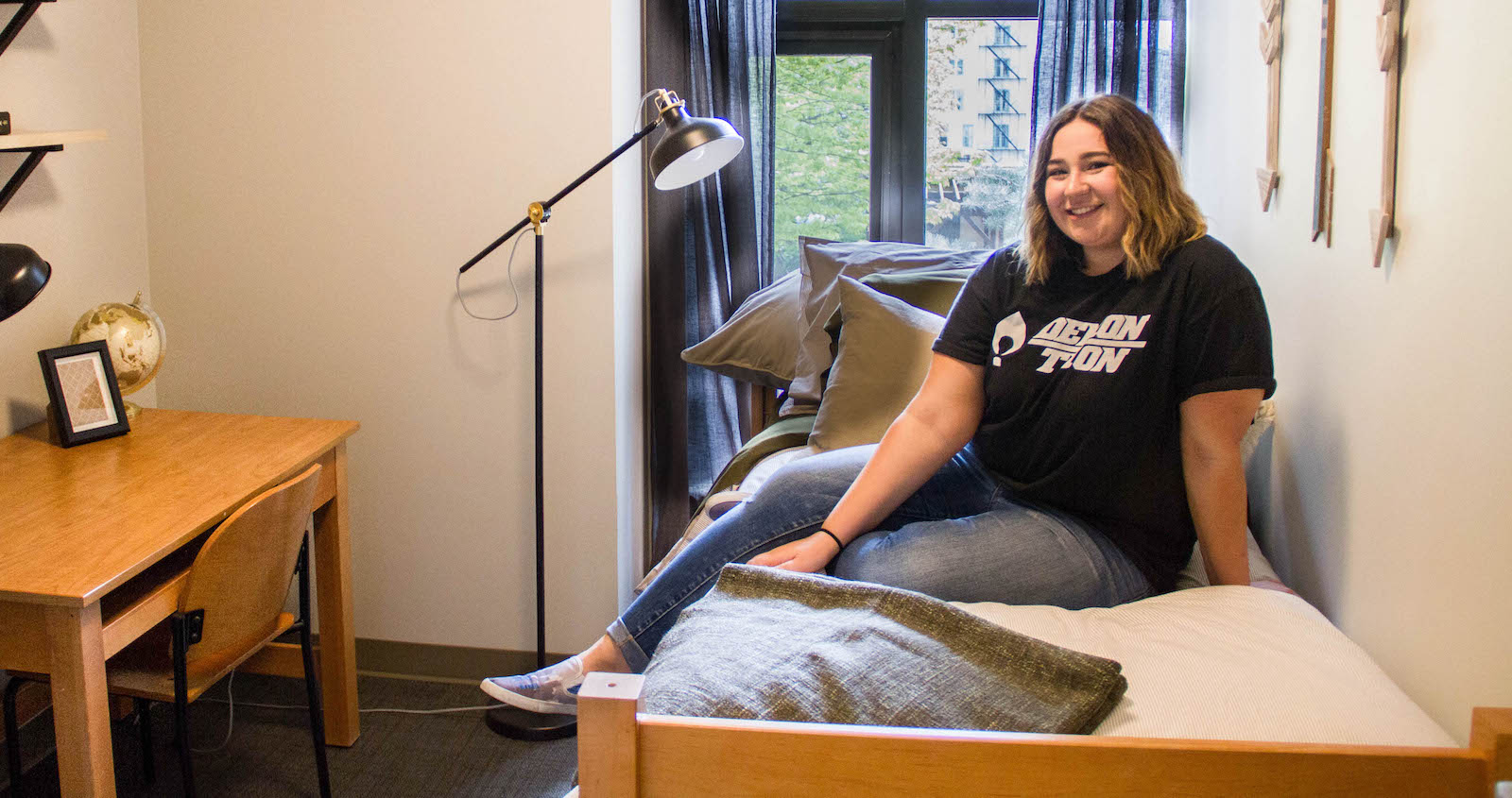 Student sitting on their bed in a University Center unit