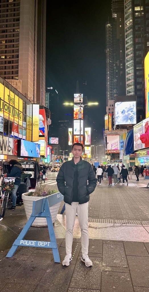 A young man stands in Times Square at night