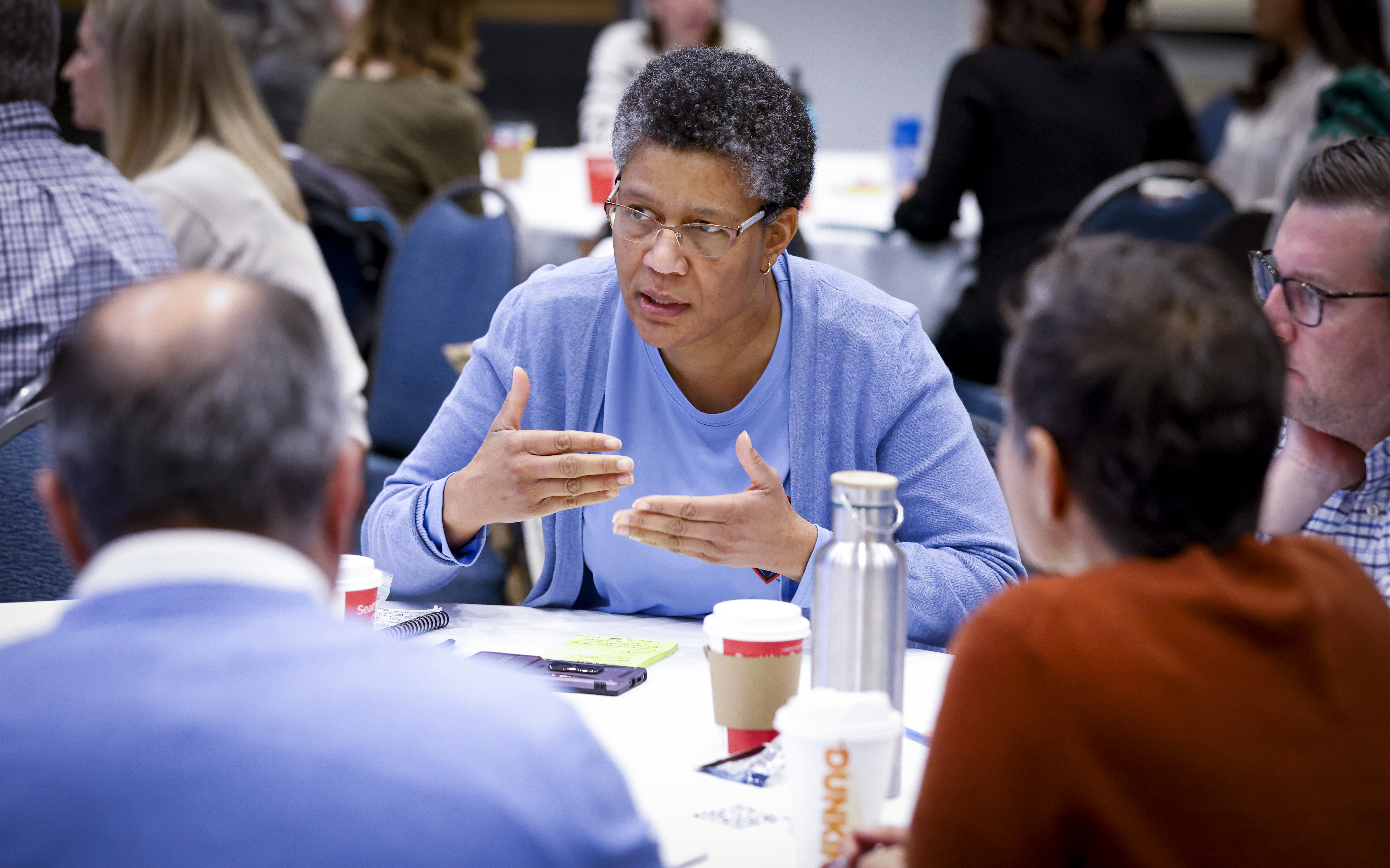 A woman sits at a table talking with colleagues. A woman sits at a table talking with colleagues.