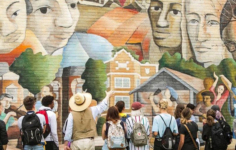 Group of students in front of outdoor mural.